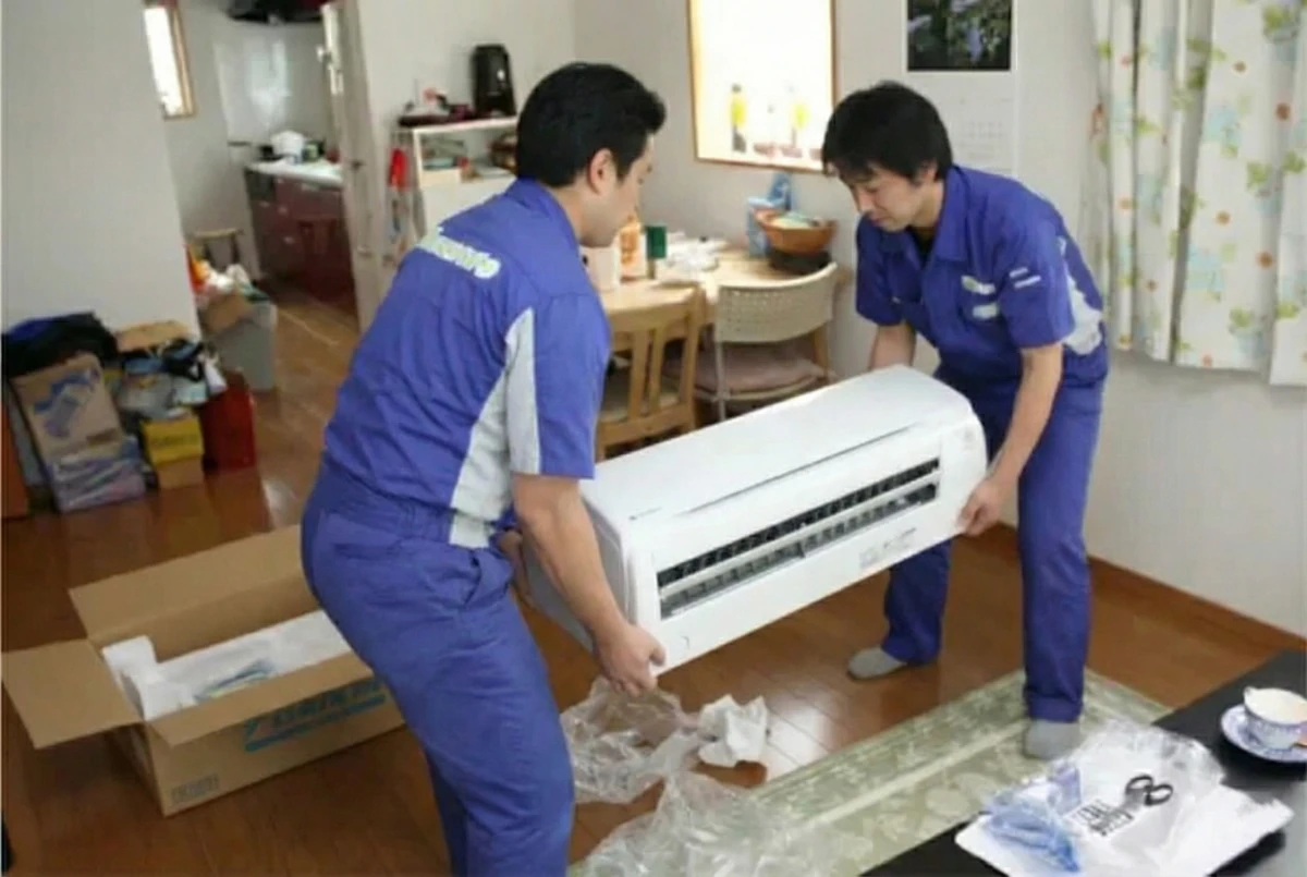 エアコンを２人で運んでいます