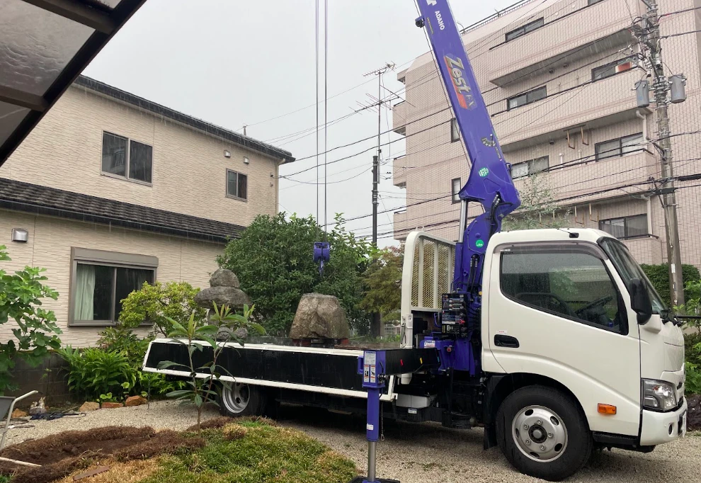 クレーン付きトラックを据えた庭石撤去の現場